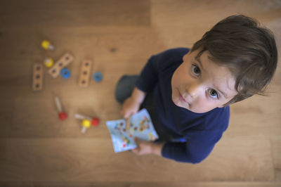 High angle view portrait of boy playing on floor