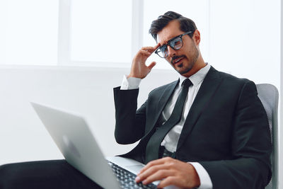 Portrait of businessman using laptop at office