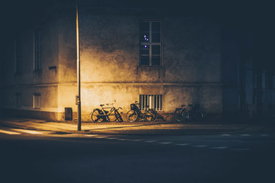 Bicycle by illuminated building at night