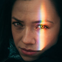 Close-up portrait of woman with spectrum falling on face