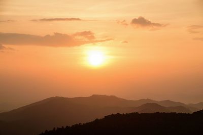 Scenic view of silhouette mountains against orange sky