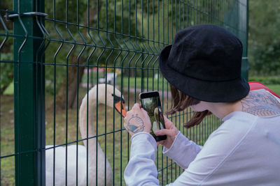 Woman photographing swan with mobile phone