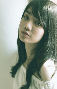 Close-up portrait of young woman against wall