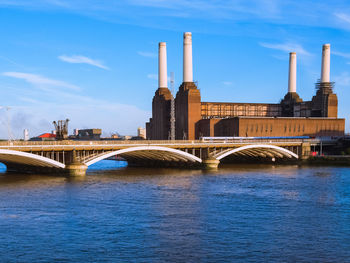 Arch bridge over river against sky in city