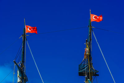 Low angle view of flags hanging against blue sky