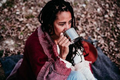 High angle view of woman drinking coffee while sitting outdoors