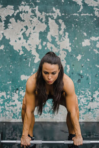 Portrait of young woman standing against wall