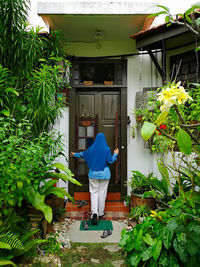 Rear view of woman standing by flowering plants