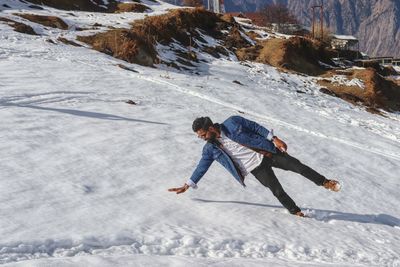 Full length of man falling on snow covered mountain during winter