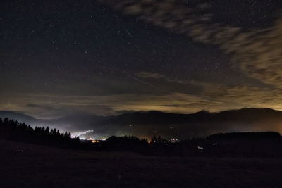 Silhouette landscape against star field at night