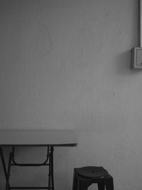 Empty chair and table against wall at home