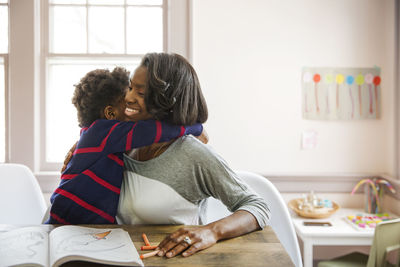 Side view of loving boy embracing mother at home