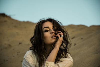 Portrait of beautiful young woman in desert against sky