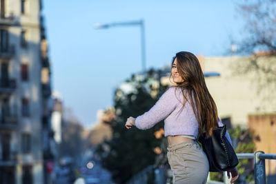 Midsection of woman standing against sky in city