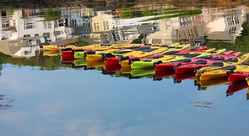 Multi colored moored boats in water against sky