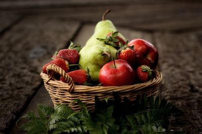 Close-up of various fruits in wicker basket on table