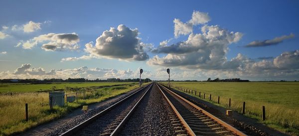 Empty railroad track amidst field against sky