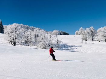 Man skiing on snow covered mountain against sky