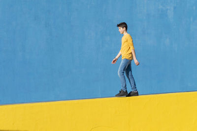 Young man standing against yellow wall