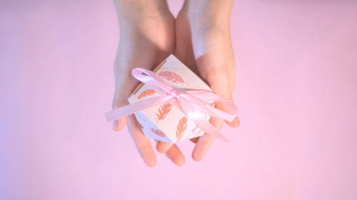 Midsection of woman holding umbrella against pink background