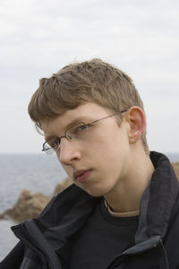 Close-up portrait of teenage boy against sky