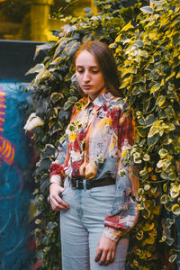 Young woman looking away while standing in autumn leaves