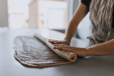 View of woman's hand rolling dough