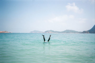 Low section of person diving in sea against sky