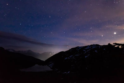 Scenic view of silhouette mountains against sky at night