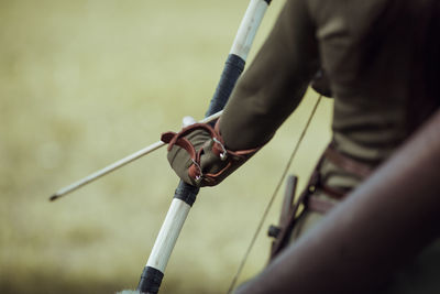 Midsection of archer holding bow and arrow while standing outdoors