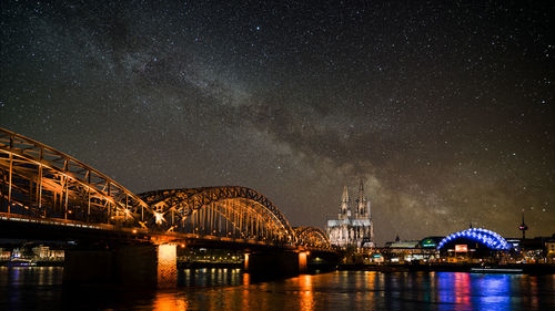 Illuminated bridge over river against sky at night