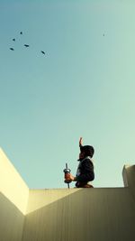 Low angle view of man flying kite against clear sky