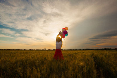 Portrait of woman holding balloons against sky