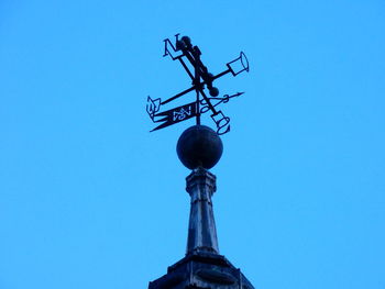 Low angle view of weather vane against clear blue sky