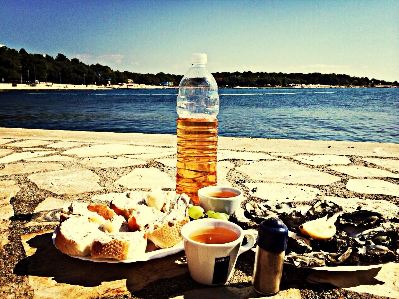 water, sea, clear sky, food and drink, beach, tranquil scene, shore, tranquility, table, drink, nautical vessel, scenics, sky, moored, sunlight, nature, sand, wood - material, day, blue