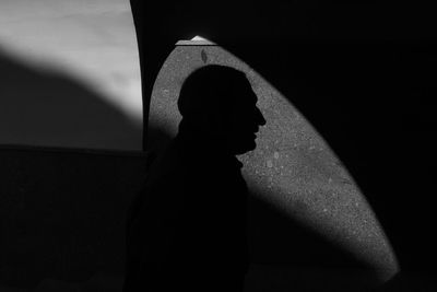 Silhouette of woman standing against wall