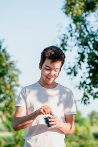 Man holding camera while standing against sky