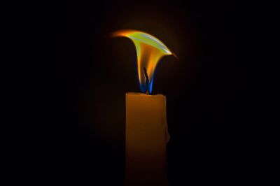 Close-up of illuminated candle against black background