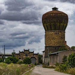 Scenic view of building in town against cloudy sky