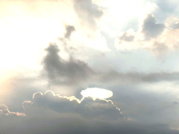 Low angle view of sunlight streaming through clouds