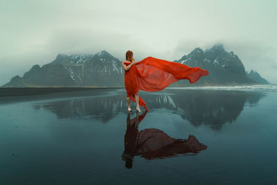 Woman in red dress with waving cape on beach scenic photography