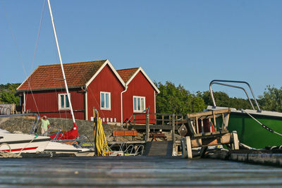 View of fishing boats moored by building against blue sky