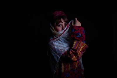 Portrait of woman standing against black background