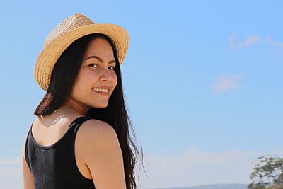 Portrait of smiling young woman against sky