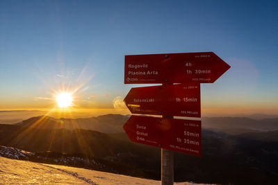 Information sign on mountain against sky during sunset
