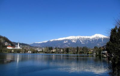 Scenic view of lake and mountains against clear blue sky