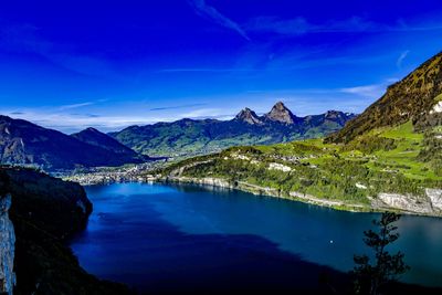 Scenic view of lake by mountains against blue sky