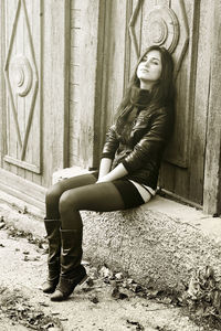 Full length portrait of woman sitting outdoors