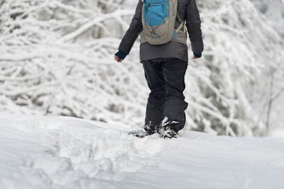 Low section of man walking on snowy field