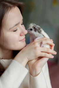 Girl holds cute hedgehog in her hands. portrait of pretty curious muzzle of animal. favorite pets. 